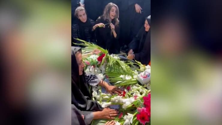 אישה גוזרת את שיערה מעל קבר אחיה, שנהרג במהומות החיג'אב באיראן