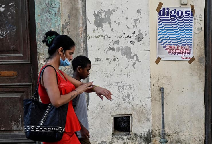 קובה משאל עם נישואים חד מיניים להט"ב איש וילד עוברים ליד כרזה של מחנה ה כן ב הוואנה