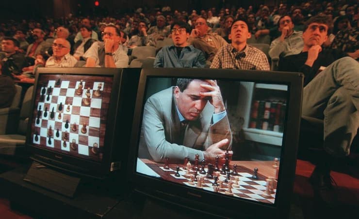 אנשים צופים במסכים בגארי קספארוב במשחק שחמט מול המחשב כחול עמוק ב-1997