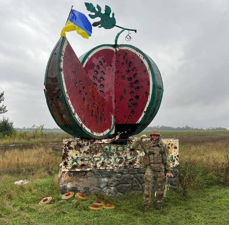 חייל אוקראיני עומד מול אנדרטה בכפר באזור חרסון מלחמה רוסיה אוקראינה