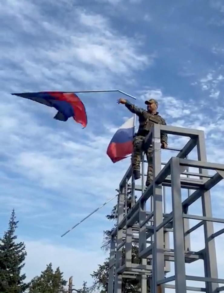 חייל אוקראיני מניף את דגל רוסיה ה מעל אנדרטה ב עיירה לימאן ששוחרה במחוז דונייצק דונבאס אוקראינה מלחמה רוסיה