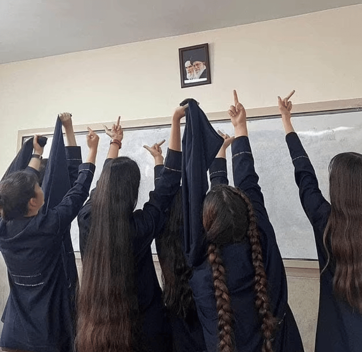 תלמידות תיכון ב איראן מפנות אצבע משולשת לתמונותיהם של המנהיג העליון עלי חמניאי וקודמו רוחאללה חומייני בכיתה בבית ספר תמונה שהופצה ברשתות החברתיות ופורסמה גם בגרדיאן הבריטי