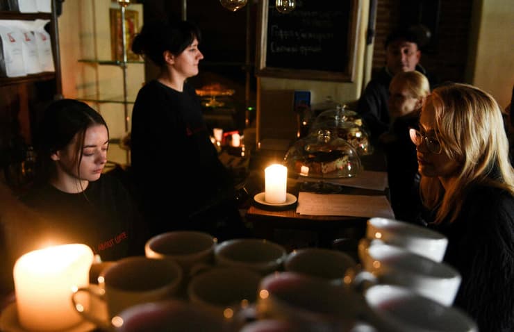 מלחמת אוקראינה רוסיה שותים קפה בבית קפה ב לבוב בחושך בגלל הפסקת החשמל אחרי התקיפות