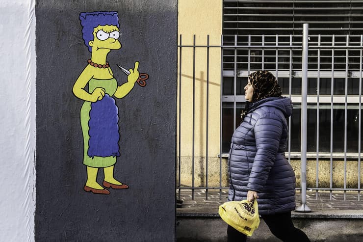 איטליה מילאנו ציור קיר הזדהות עם מחאת ה חיג'אב ב איראן מארג' סימפסון גוזרת את שיערה ומפנה אצבע משולשת