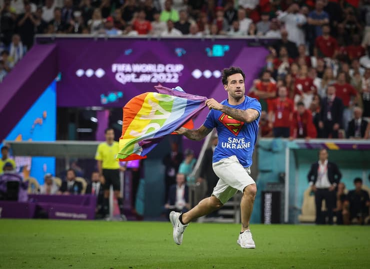 אוהד פורץ עם דגל הגאווה למגרש במשחק בין פורטוגל לבין אורוגוואי בגביע  העולם בקטאר