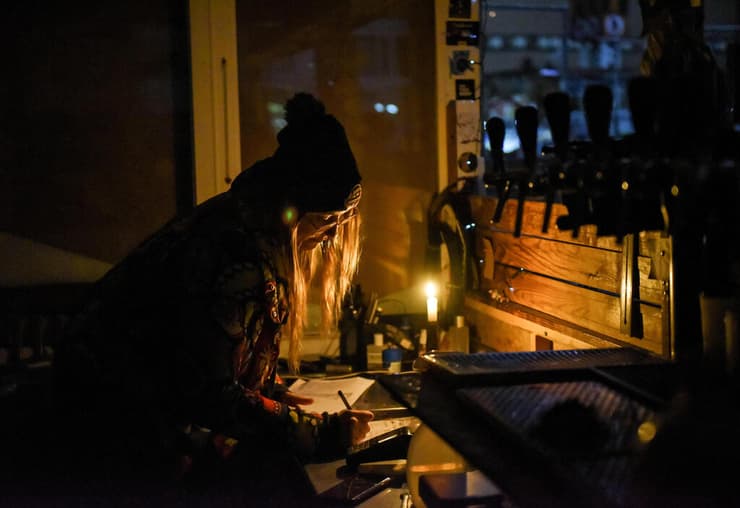 אוקראינה אישה מוכרת בירה בזמן הפסקת חשמל קייב