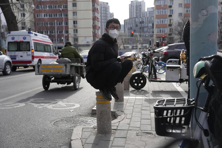צעיר סיני מחכה ליד בית חולים ב בייג'ינג בצל חשש מהתפרצות אחרי הסרת הגבלות קורונה