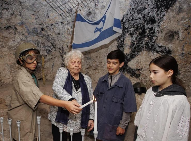 פלמחניקית וילדים מדליקים נרות במערת הפלמ"ח