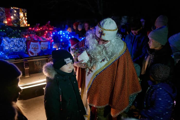 ילדים מקבלים מתנות מאדם המחופש ל ניקולאוס הקדוש (המקור לדמות סנטה קלאוס) ב סלוביאנסק דונייצק אוקראינה לרגל חג המולד בצל מלחמה מול רוסיה