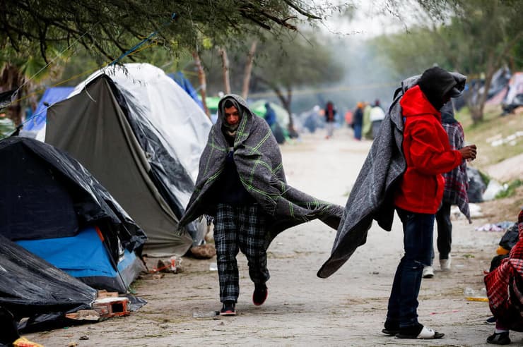 מהגרים ב גבול ארה"ב מקסיקו מתחממים בצל קור עז סופה במחנה מאולתר בעיירה המקסיקנית  מטמורוס סמוך ל טקסס