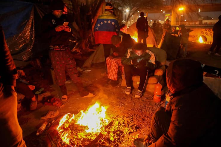 מהגרים ב גבול ארה"ב מקסיקו מתחממים בצל קור עז סופה במחנה מאולתר בעיירה המקסיקנית סיודאד חוארס סמוך ל טקסס
