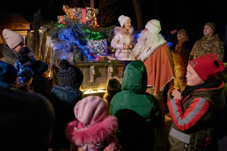 ילדים מקבלים מתנות מאדם המחופש ל ניקולאוס הקדוש (המקור לדמות סנטה קלאוס) ב סלוביאנסק דונייצק אוקראינה לרגל חג המולד בצל מלחמה מול רוסיה