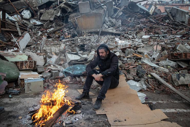 גבר מחכה ליד האש לחדשות על יקיריו שלכודים מתחת להריסות ב הטאי טורקיה רעש רעידת אדמה