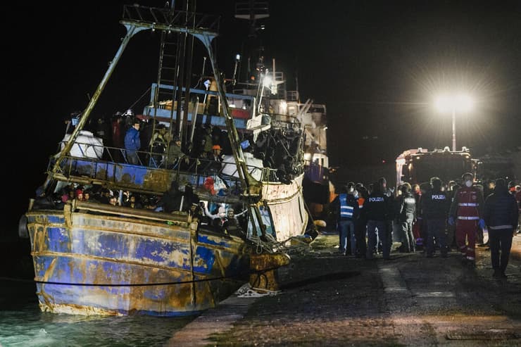שוטרים עורכים חיפוש על סירת דיג שעליה 500 מהגרים שחולצו מלב ים ב נמל קרוטונה ב איטליה 11 מרץ