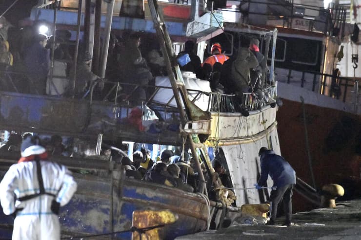שוטרים עורכים חיפוש על סירת דיג שעליה 500 מהגרים שחולצו מלב ים ב נמל קרוטונה ב איטליה 11 מרץ