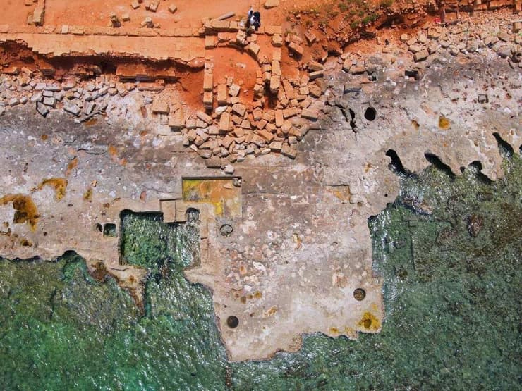 תמונת מזל"ט עדכנית (2022) המציגה נזק למבנים ארכיאולוגיים בנמל העתיק של אפולוניה (מזרח לוב) שנגרם משחיקת החוף