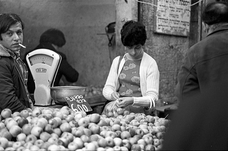 אשה קונה תפוחי עץ ב דוכן בשוק מחנה יהודה