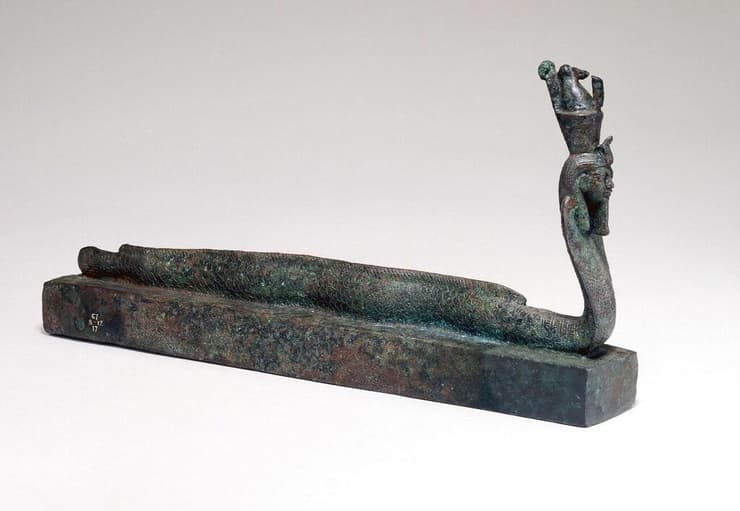 ארון קבורה של בעלי חיים, מעליו יצור דמוי נחש קוברה עם ראש אדם פרעוני שקושר לאל המצרי הקדום הקשור לאל המצרי הקדום אתום