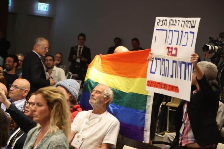 דגל גאווה ושלט מחאה הונפו בפאנל בהשתתפות שמחה רוטמן בכנס בתל אביב