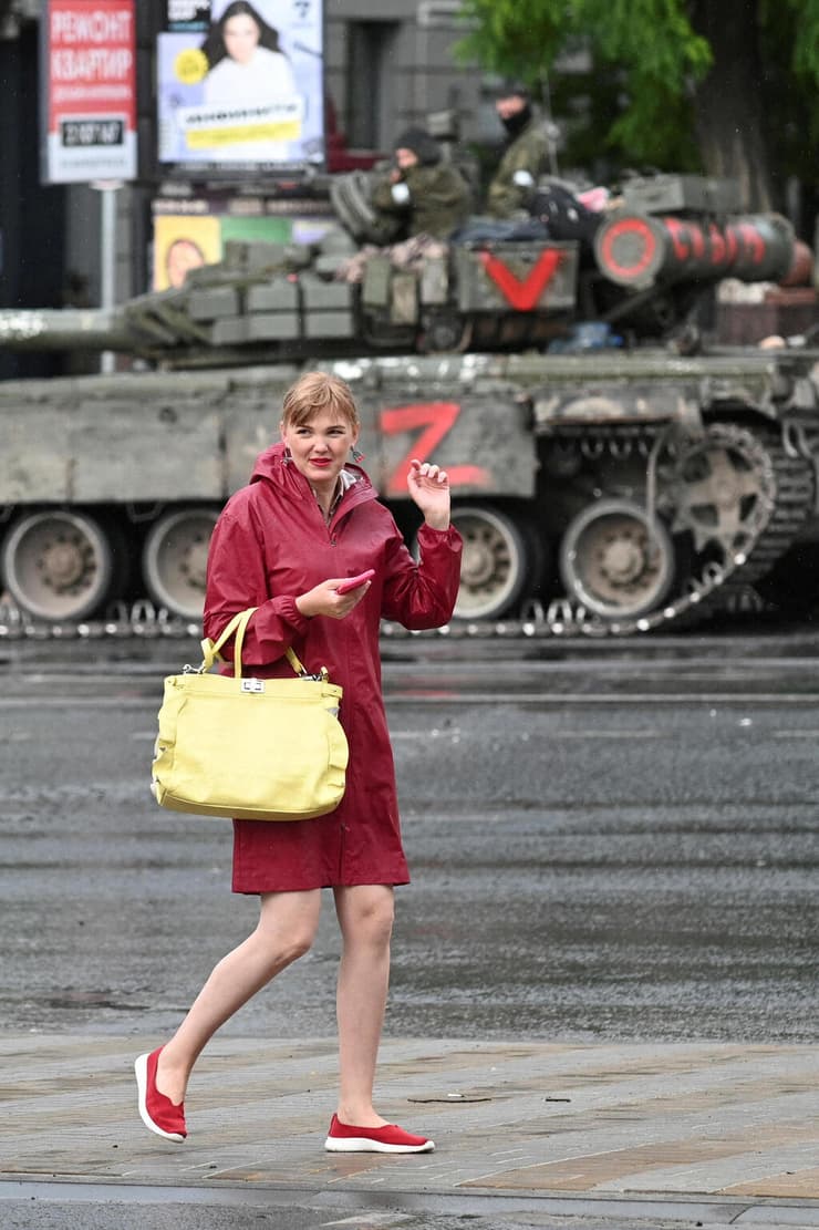 אישה חולפת על פני לוחמי קבוצת שכירי החרב הפרטית של וגנר ברחוב ליד מפקדת המחוז הצבאי הדרומי בעיר רוסטוב-על-דון, רוסיה
