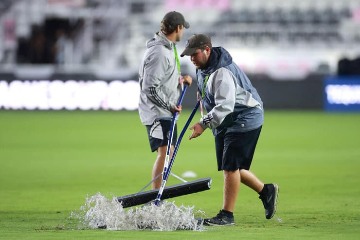 עובדי האצטדיון מנסים לייבש את כר הדשא לפני המשחק