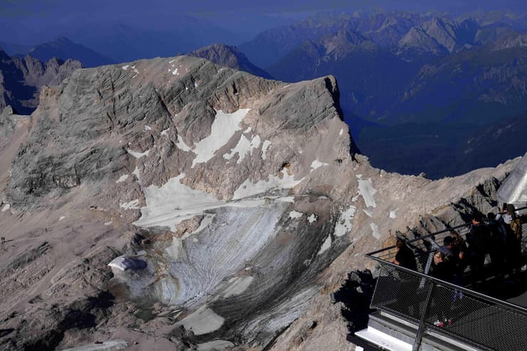 תיירים מסתכלים על קרחון שנמס באלפים