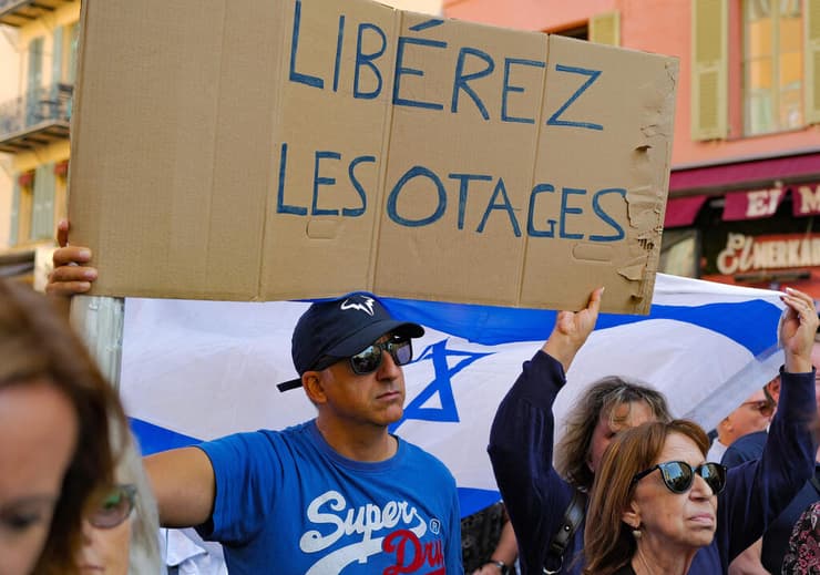 מפגין אוחז בכרזה "שחררו את בני הערובה" במהלך עצרת תמיכה בישראל בעיר ניס בריביירה הצרפתית
