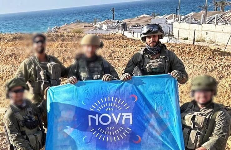 עידן עמדי וחבריו לצוות מניפים את דגל נובה על החוף בעזה