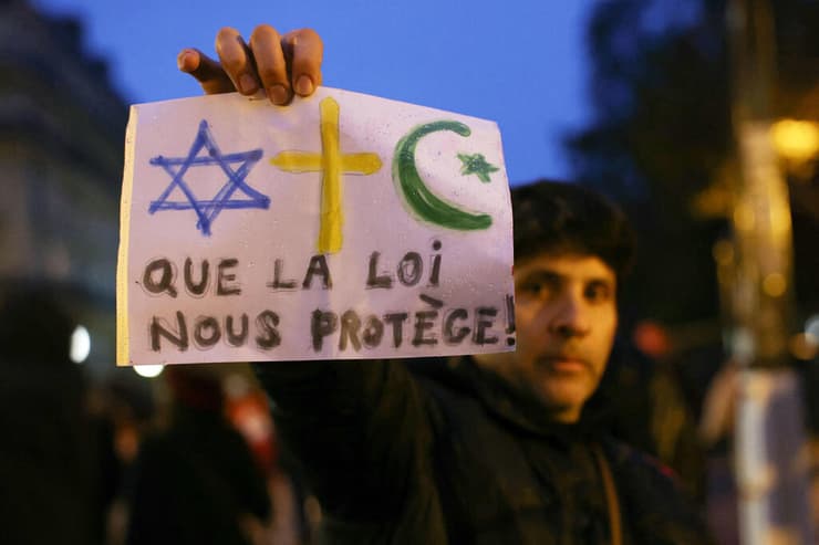 צרפת הפגנה נגד אנטישמיות פריז מפגין עם הכרזה "שהחוק יגן עלינו"