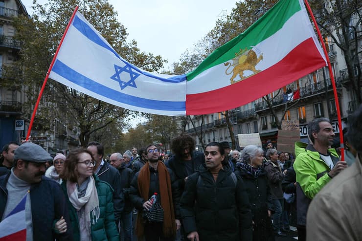 צרפת הפגנה נגד אנטישמיות פריז מפגינים עם דגל ישראל ודגל איראן של לפני המהפכה האיסלאמית