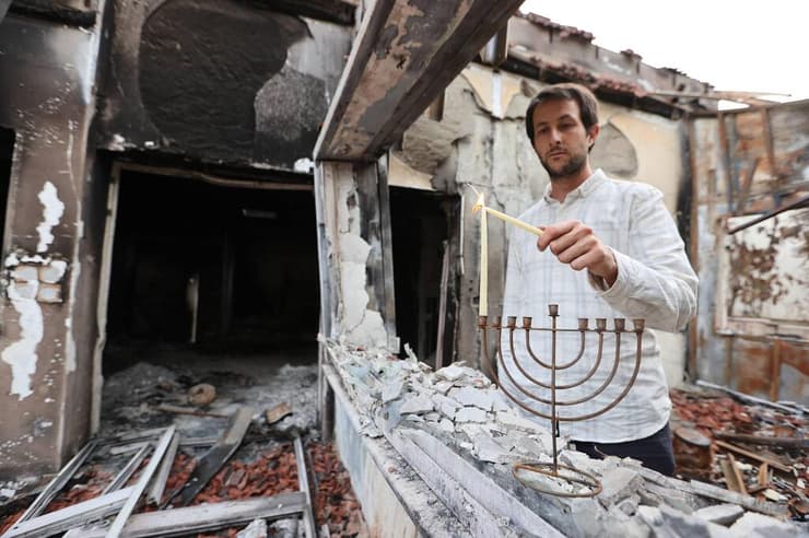 תמיר הרשקוביץ, בנם של נח ומעיינה שנרצחו בהתקפת המחבלים בבארי, מדליק נר חנוכה ראשון בחנוכייה שנשרפה בבית ההורים