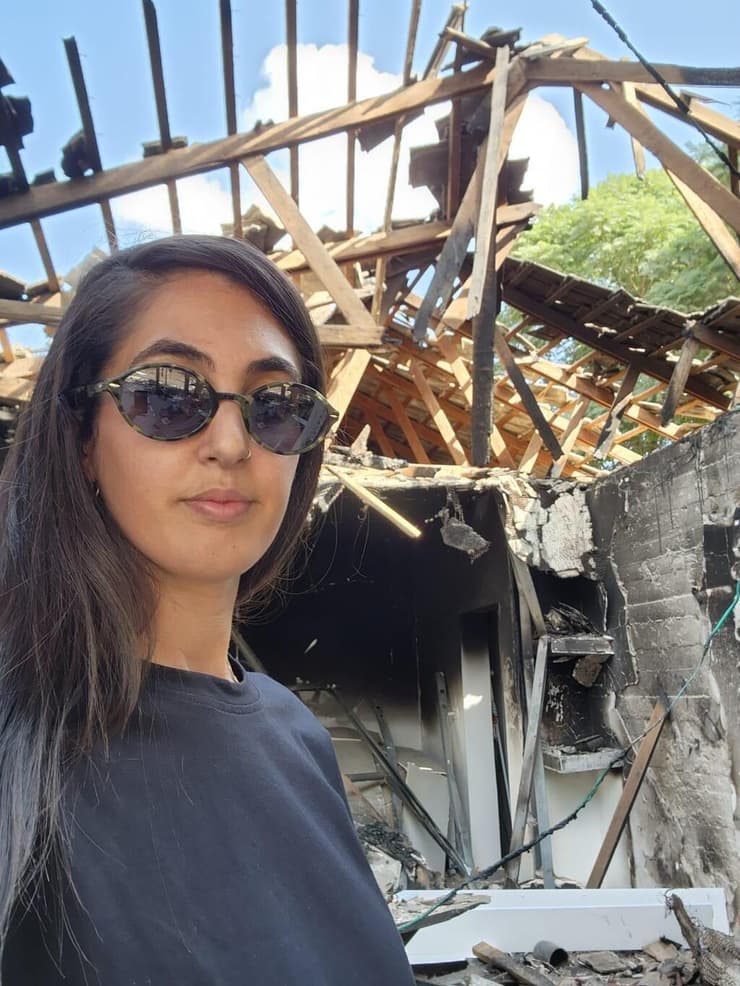 דורין כהן על רקע ביתה השרוף בכפר עזה