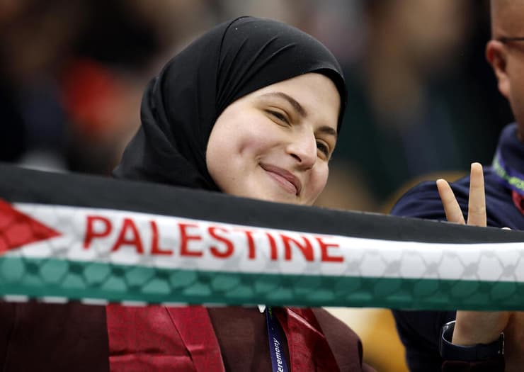 אוהדת עם דגל פלסטין ביציע בלוסייל בפתיחת אליפות אסיה