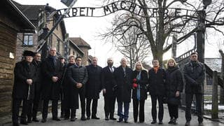 המשתתפים בכנס תחת שלט "העבודה משחררת" באושוויץ. "'לעולם לא עוד' זו לא רק סיסמה"