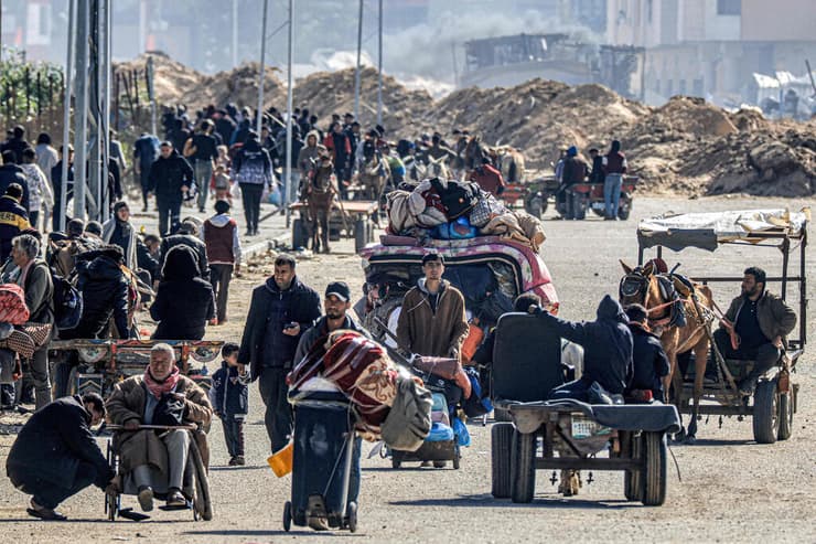 פליטים פלסטינים מתפנים מ חאן יונס כשברקע נראה דחפור של צה"ל ב רצועת עזה