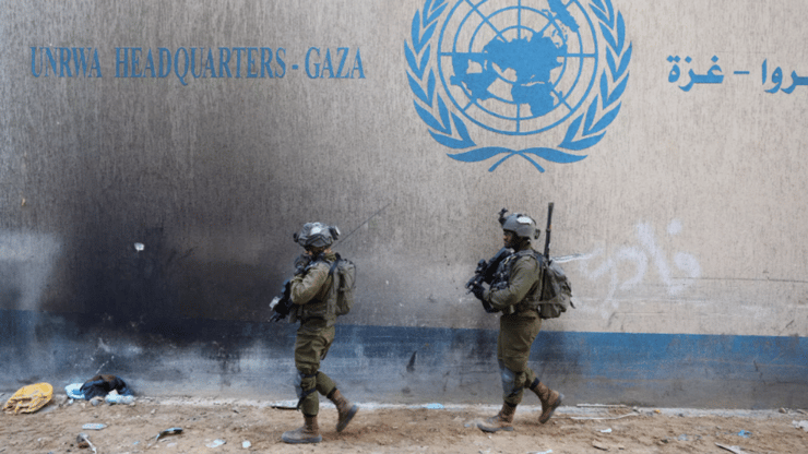 לוחמי צה"ל מול מטה אונר"א ברצועת עזה (צילום: JACK GUEZ / AFP) לוחמי צה"ל לצד סמל של אונר"א ברצועת עזה ארכיון