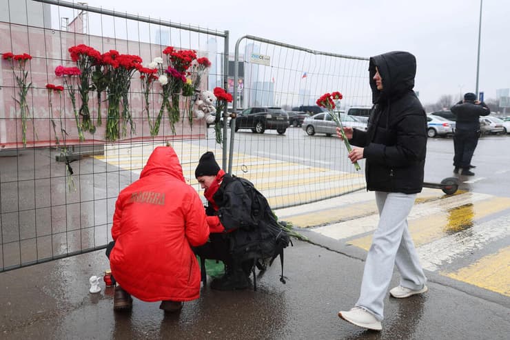 מניחים פרחים לזכר הנרצחים סמוך לזירת הפיגוע