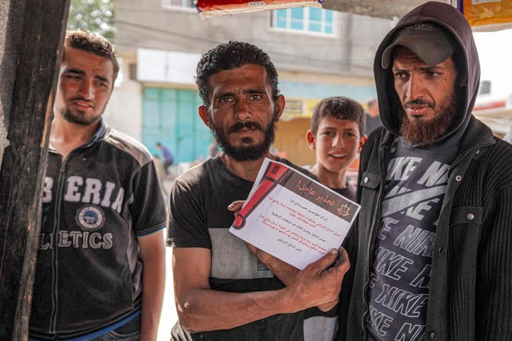 פלסטינים בדיר אל בלח מחזיקים כרוז של צה"ל