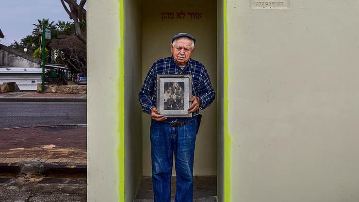 "בכל פעם שיש מטח טילים על העיר כל הבית רועד". שמיל ברקו אוחז בתמונת משפחתו במקלט הציבורי באשקלון, שבו שהה ב-7 באוקטובר (צילום: אביגיל עוזי) yk13890154