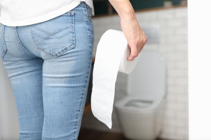 אישה הולכת לשירותים שתן נייר טואלט