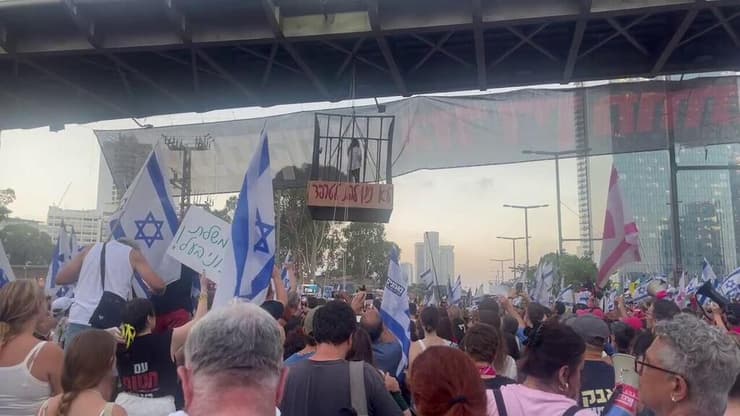 עינב צנגאוקר, אמו של החטוף מתן צנגאוקר, נכנסה בכלוב שהתרומם מעל כביש בגין