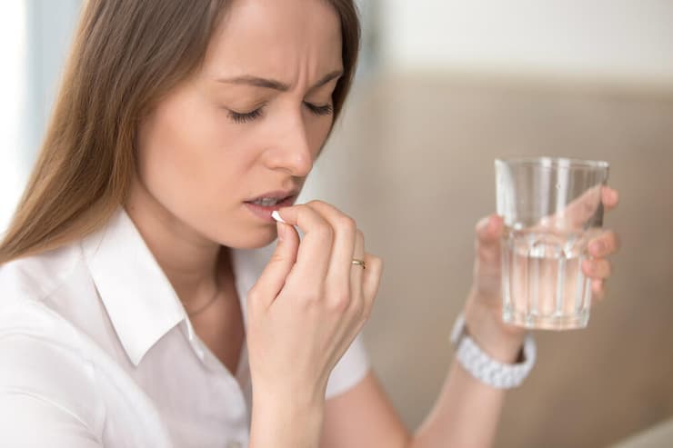 להתחיל במשככי כאבים פשוטים. כאבי מיגרנה (צילום: shutterstock) אישה נוטלת תרופה כדור משככי כאבים