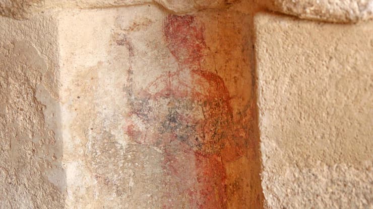 דמות אוחזת בטווס לפני עבודות השימור