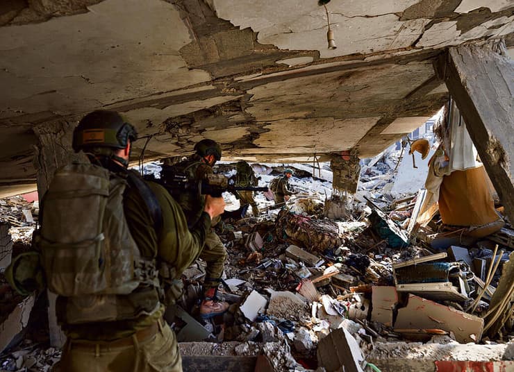 מחסה רעוע. כדי להימנע מתנועה בשטח פתוח וחשיפה לצלפים, הלוחמים נעים תחת בניין מט לנפול (צילום: זיו קורן) yk14125605