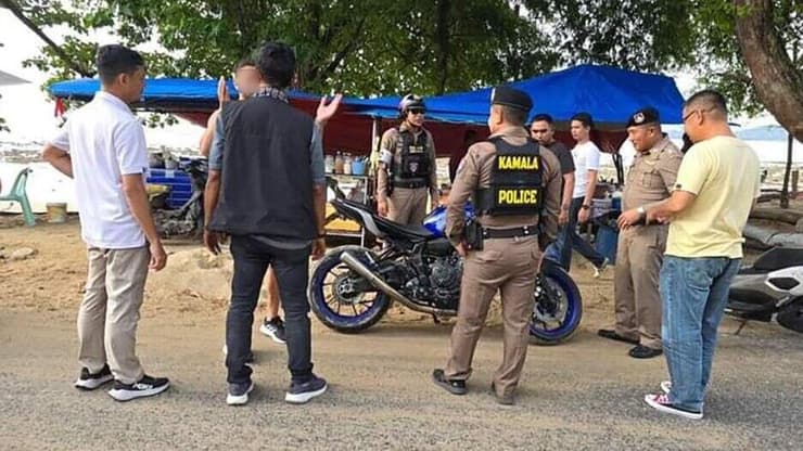 השוטרים מעכבים את הרוכב הישראלי לחקירה (צילום שהפיצה משטרה תאילנד לכלי התקשורת) תייר ישראלי רכב על אופנוע בחוף הים בתאילנד