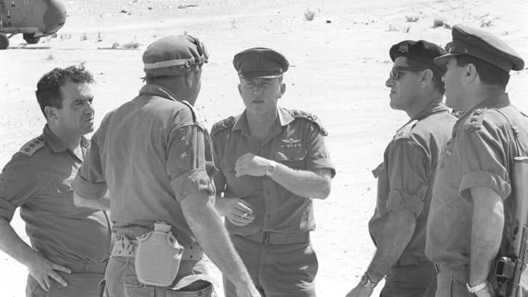 הרמטכ"ל רא"ל יצחק רבין בשיחה עם מפקד פיקוד הדרום אלוף ישעיהו (שייקה) גביש, חובש כומתה בגבו למצלמה. משמאלו אל"מ אברהם (אברשה) טמיר, רמ"ח תכנון וארגון באג"ם, קיצוני מימין אל"מ יעקב חפץ יועץ כספי לרמטכל, ובינו ובין רבין ניצב אל"ם מרדכי ציפורי, מח"ט 14.