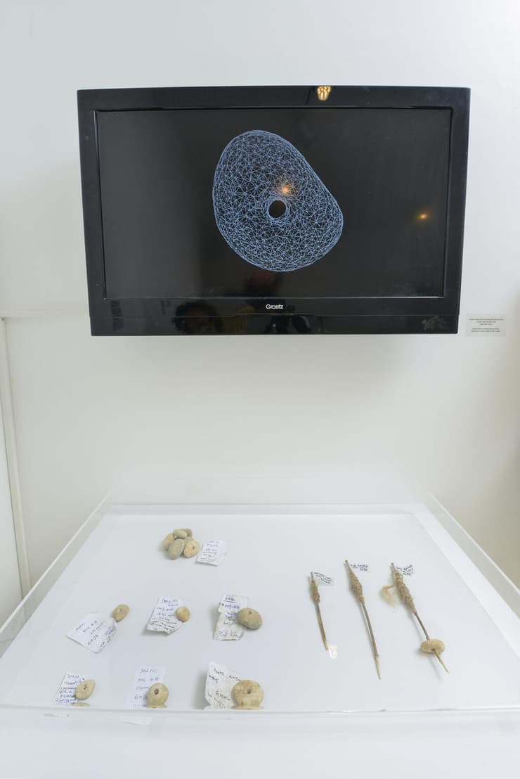 המודל התלת-ממדי של האבן המחוררת שאותרה באתר נחל עין גב II, לצד ממצאים נוספים שאותרו בשטח האתר, מתוך תערוכה בבית בנימיני