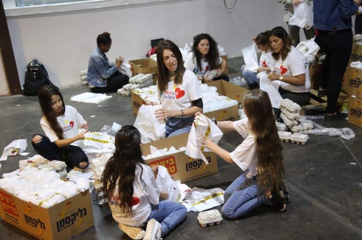 מתנדבים לאריזת חבילות מזון למשפחות נזקקות לקראת חג הפסח בהאנגר 11 בנמל תל אביב