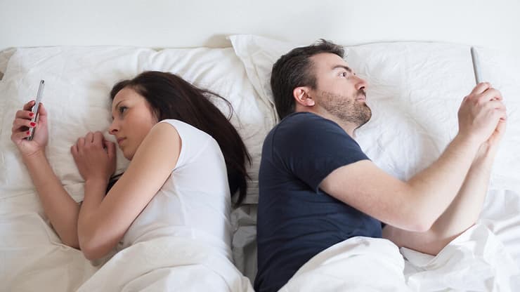 גבר ואישה בעת שימוש בטלפון במיטה