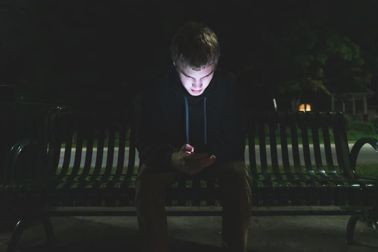 גבר יושב על הספסל ומסתכל בטלפון